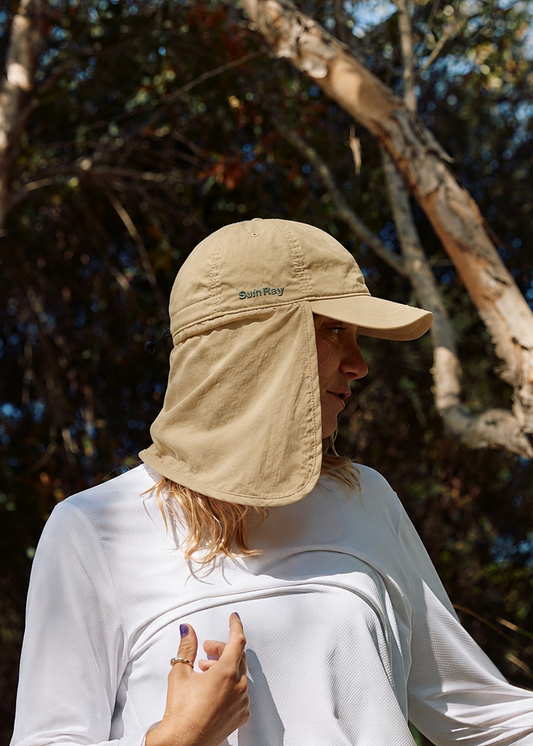 A woman wearing a stone UPF50+ sun hat with a neck flap and a white long-sleeve shirt.